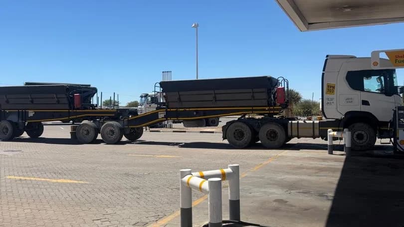Haul trucks parked in a line at a desert road stop under a canopy roof