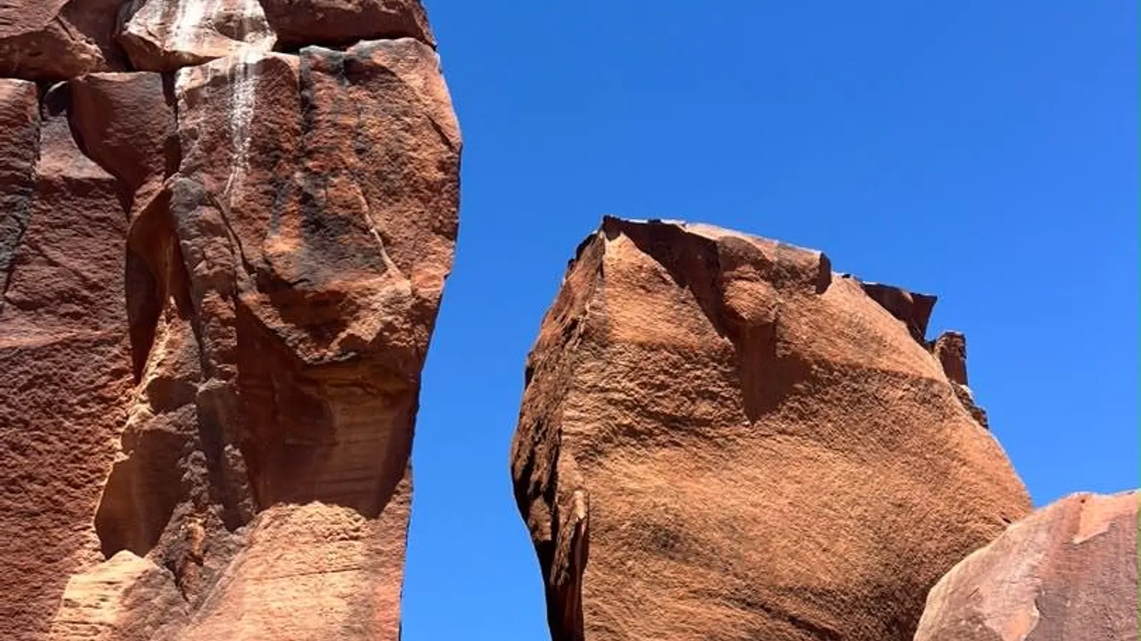 Tall weathered rock walls of a desert gorge closing in overhead against the sky