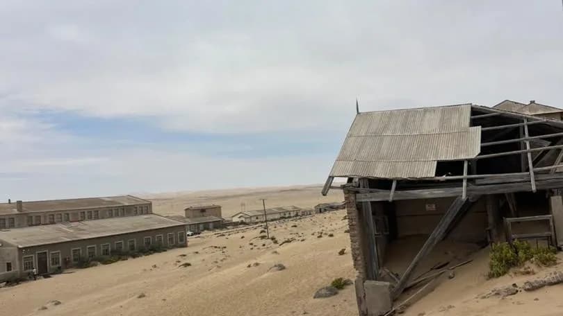 Weathered wooden buildings being slowly buried by advancing desert sand