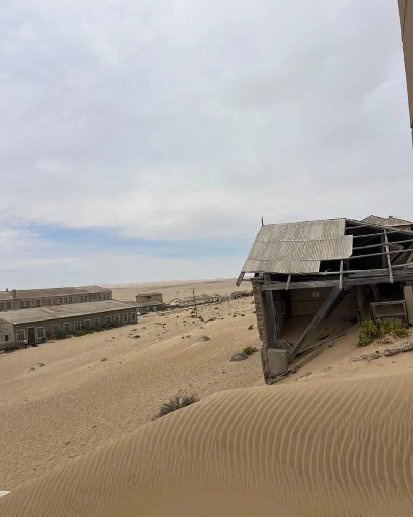 Weathered wooden buildings being slowly buried by advancing desert sand